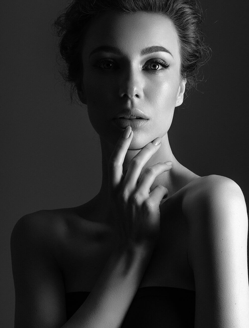 Black and white headshot of a woman caressing her chin