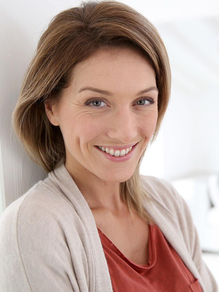 Headshot of a smiling woman leaning on a doorway