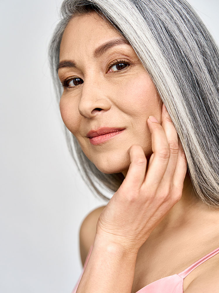 Headshot of a grey hair woman caressing her cheek