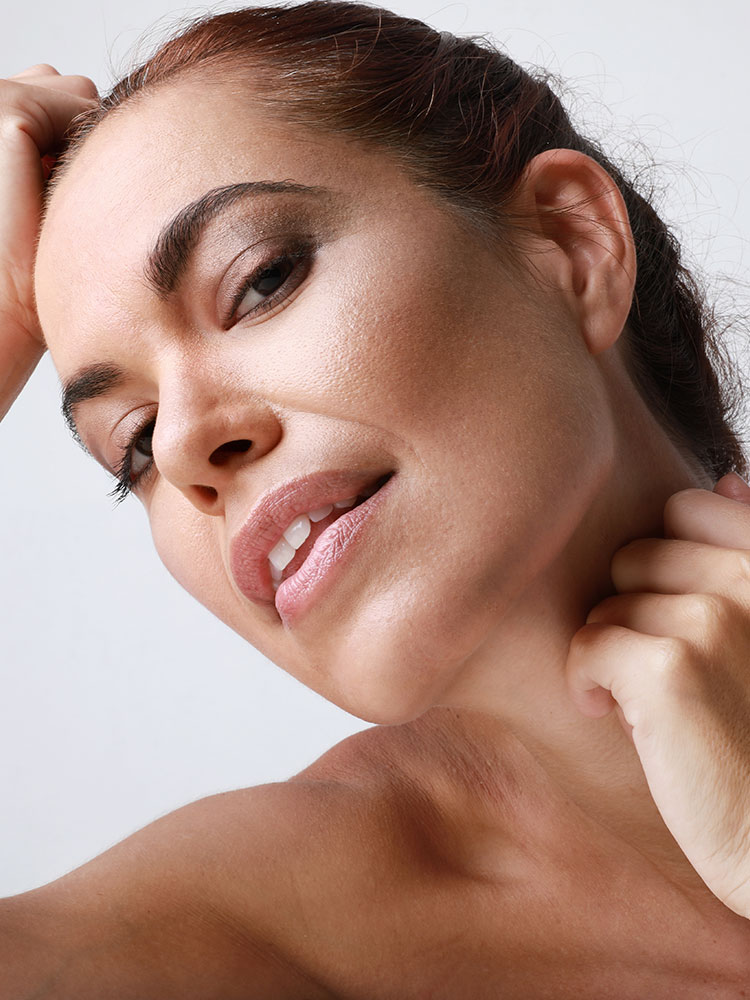 Close up of a woman leaning her head back with a sculpted jaw line